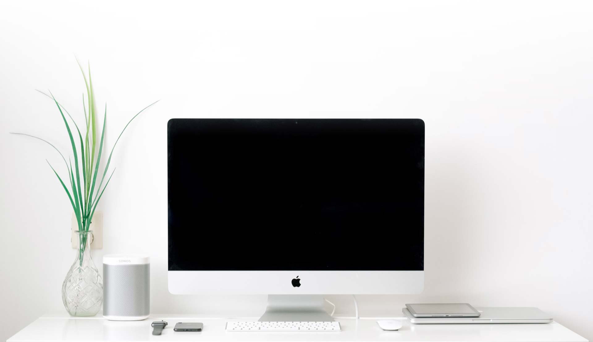 Sonos speakers on a white desk next to an iMac